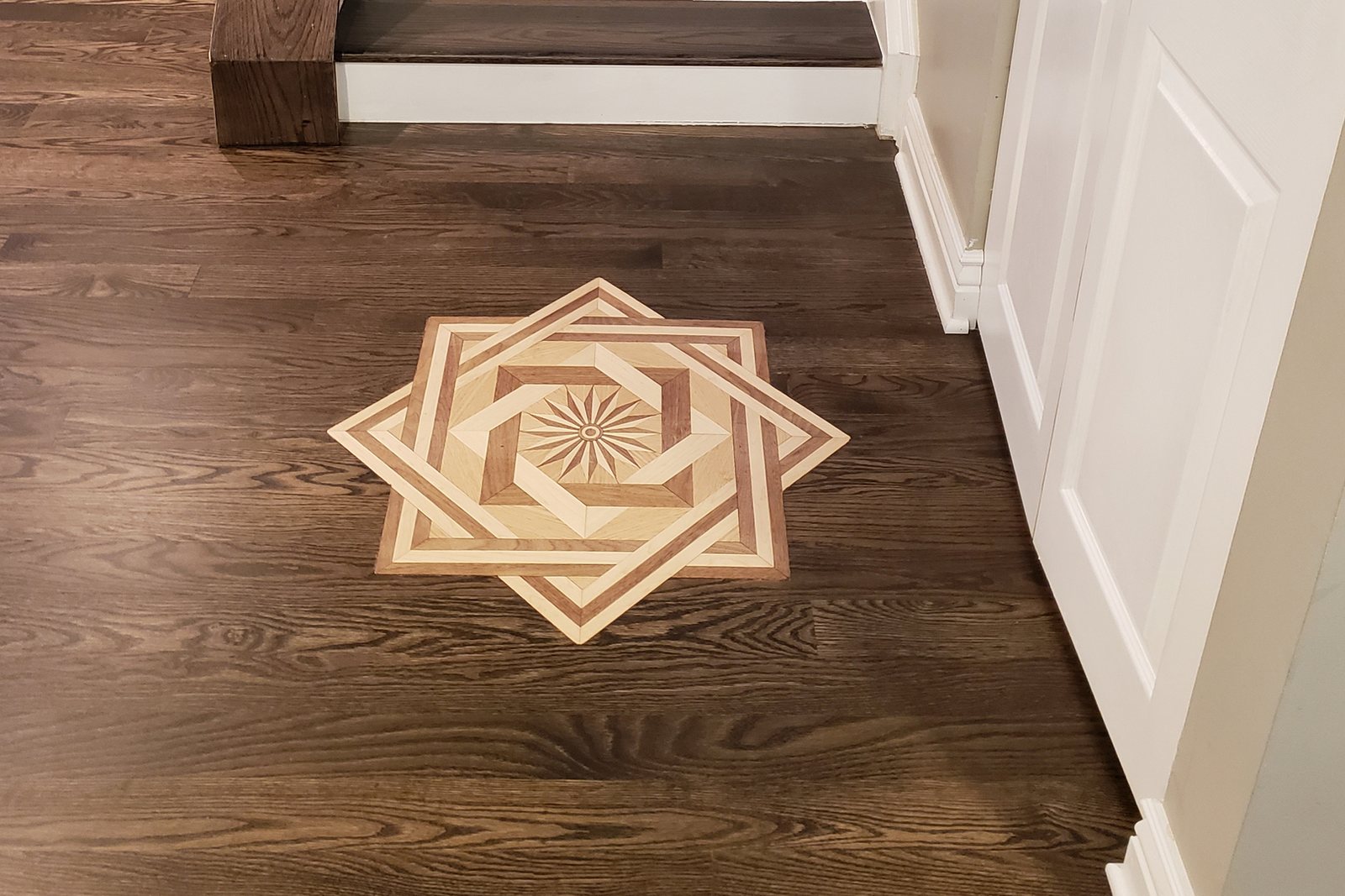 Custom inlaid wood medallion in a dark-stained oak floor installed by Floormaster